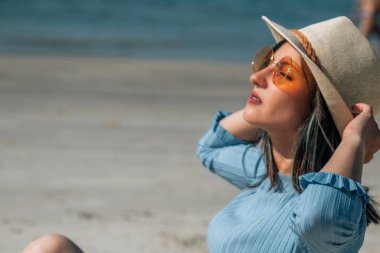 Kumsalda oturan rahat genç bayan.