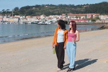 Kumsalda rahatça yürüyen bir çift.