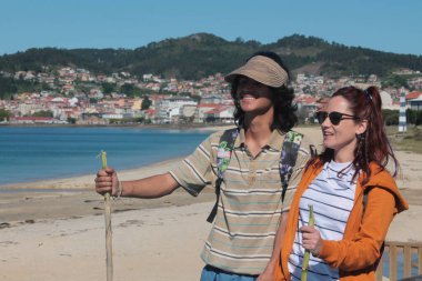 Sırt çantalı turist çift plaj manzarasının tadını çıkarıyor.