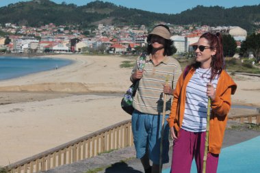 Sırt çantalı turist çift plaj manzarasının tadını çıkarıyor.