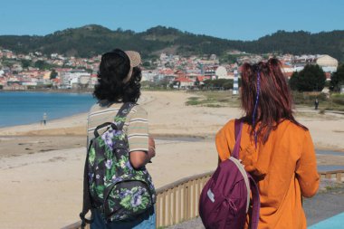 Sırt çantalı turist çift plaj manzarasının tadını çıkarıyor.