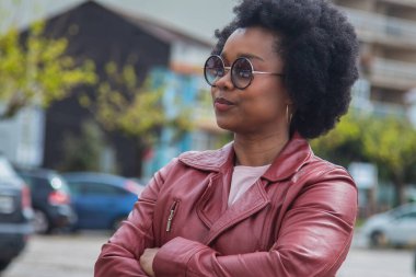 Sokakta kollarını kavuşturmuş Latin bir kadın.