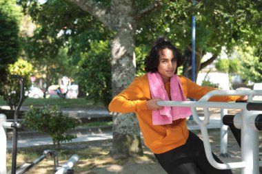 Parkta eğitim aletleri üzerinde çalışan genç adam.