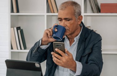 Ofiste ya da işyerinde orta yaşlı bir işadamı telefonla konuşuyor.