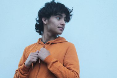 Duvarda svetşört giymiş genç Latin bir adam.