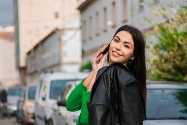 Gülümseyen kadın cep telefonuyla sokakta