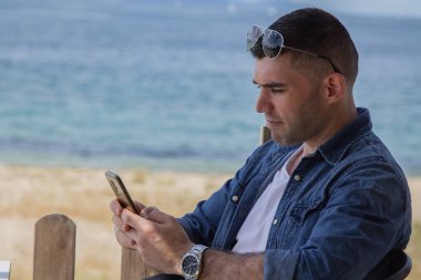 Telefon ve plaj geçmişi olan genç bir adam.