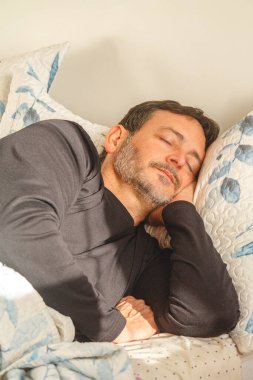 Olgun bir adamın evdeki rahat yatağında huzurlu bir uyku çekmesi iyi bir dinlenme ve sağlıklı bir uykudan faydalanması.