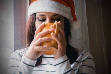 Noel 'de bardaklı genç bir kadın pencerenin yanında