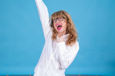 Kolları havada olgun bir kadın başarıyı kutluyor.