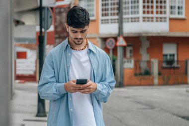 Sokak duvarında cep telefonu kullanan genç adam.