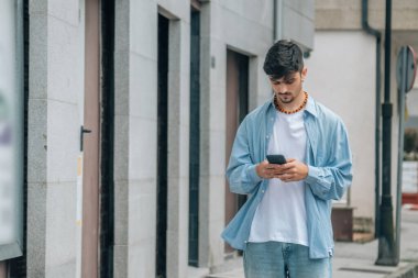 Genç adam şehirde akıllı telefon kullanıyor.