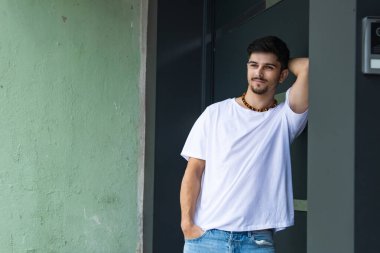 duvara yaslanmış gülümseyen genç adam