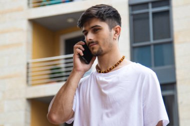 Modern genç adam sokakta akıllı telefonla konuşuyor.