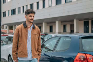 Sonbaharda şehirde yürüyen ceketli genç adam.