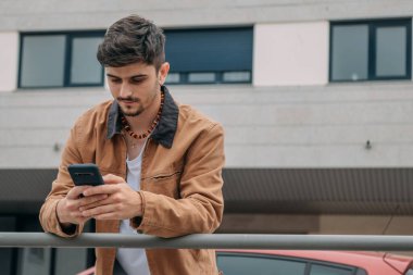 Sokakta cep telefonuna bakan sıradan bir genç.