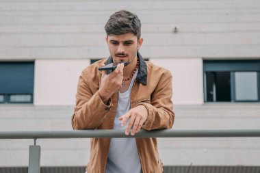 Sesli mesaj göndermek için cep telefonu kullanan sıradan bir genç.