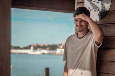 Plaj barındaki genç adam denizi düşünüyor.