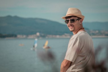 Sahilde oturan genç adam denize bakıyor.