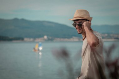 Genç adam sahilde oturmuş denize bakıyor.