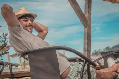 Plaj barında oturan mutlu, rahat genç adam.