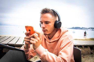 Bilgisayarlı ve dışarıda telefon kullanan genç bir adam.