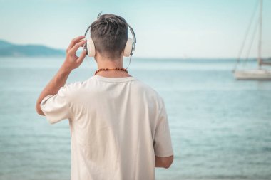 Sahildeki genç adam kulaklık takıyor.
