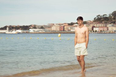 Kumsalda yürüyen rahat genç adam.