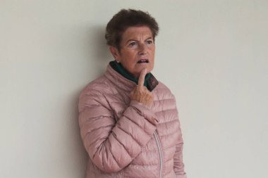 Duvarda düşünceli bir jest yapan son sınıf öğrencisi kadın.