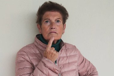 Yaşlı kadın duvara yaslanmış düşünüyor.