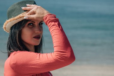 Plajda hasır şapkalı genç bir kadının portresi.