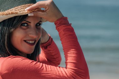 Plajda hasır şapkalı genç bir kadının portresi.