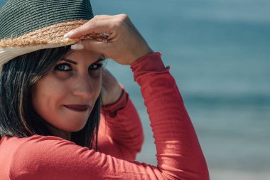 Plajda hasır şapkalı genç bir kadının portresi.