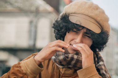 Sokakta öksüren genç adam.