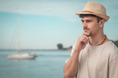 Sahilde dalgın ve çekici bir genç adam.