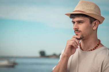 Sahilde dalgın ve çekici bir genç adam.