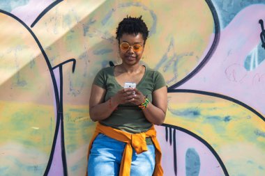 şehir kadını akıllı telefon kullanarak duvara yaslanıyor