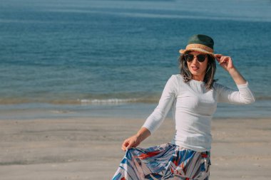 Genç bayan deniz kenarında yürürken eğleniyor.