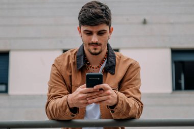 Sokakta cep telefonu kullanan sıradan bir genç.