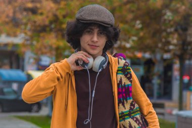 Sıradan bir genç adam sokakta müzik dinlemek için kulaklık takıyor.