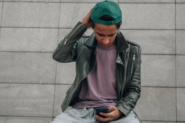 Genç çocuk cep telefonunu açık havada kullanıyor.