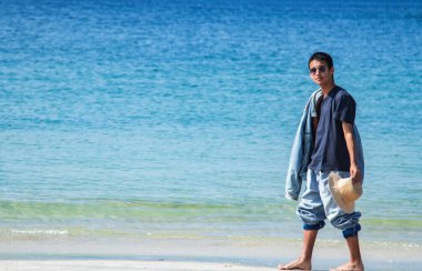 Şapkalı genç adam sahilde eğleniyor.