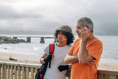 Baba ve oğul açık havada eğlenirken baba akıllı telefonu kullanıyor.