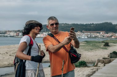 Baba oğul selfie çekiyor ya da açık havada cep telefonuyla canlı video çekiyor.