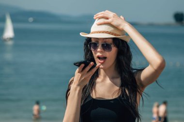 Yaz plajı yaşam tarzı. Akıllı telefondan telefon uygulaması kullanan genç bir kadın.