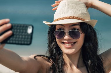 Turist kadın selfie çekiyor ya da cep telefonuyla canlı video çekiyor.