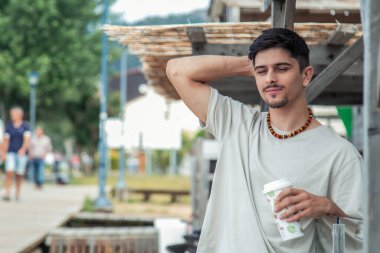 Genç adam plaj barında rahatlamış kahve içiyor.