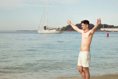 Kumsalda kollarını açmış bekleyen mutlu bir adam. 