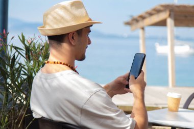 Plaj barında cep telefonu kullanan genç bir adam.