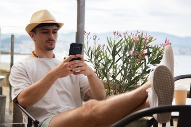 Plaj barında cep telefonu kullanan genç bir adam.